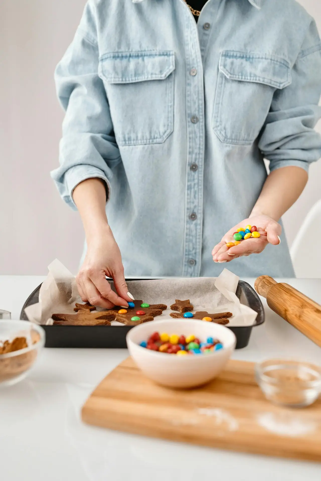 A person decorates festive gingerbread cookies with colorful candies, capturing the essence of holiday baking.