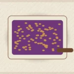 Cinnamon plum crumble in a baking dish with bubbling fruit, oat topping, and a serving spoon.