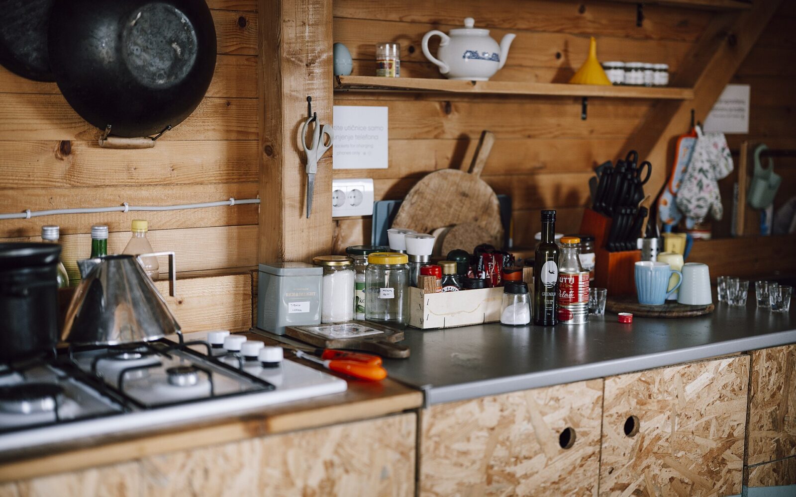 Glass jars, wooden tools, and folded linens on a lived-in kitchen counter.