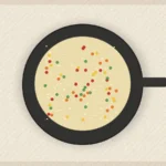 Vegetable rice skillet with peas, carrots, red pepper, herbs, and lemon on top.